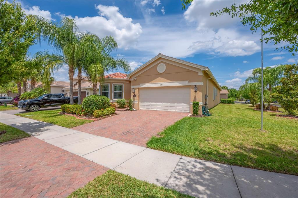 A single-story house with a brick driveway, two-car garage, and palm trees in the front — 4853 GRAND BANKS DRIVE, WIMAUMA, FL