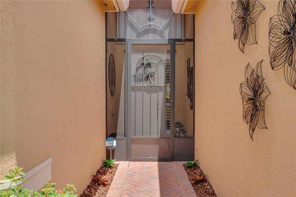 A brick walkway leads to a front door with a decorative metal screen door — 4853 GRAND BANKS DRIVE, WIMAUMA, FL