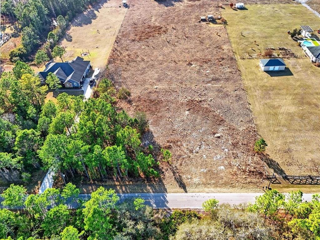 An aerial view shows a large, cleared rectangular lot situated between two residential properties — SWEET HILL ROAD, POLK CITY, FL