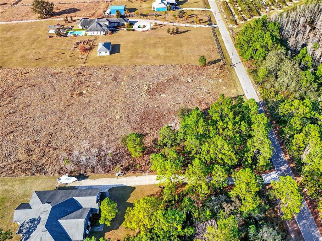 An aerial view shows a large, cleared residential lot adjacent to a road and trees — SWEET HILL ROAD, POLK CITY, FL