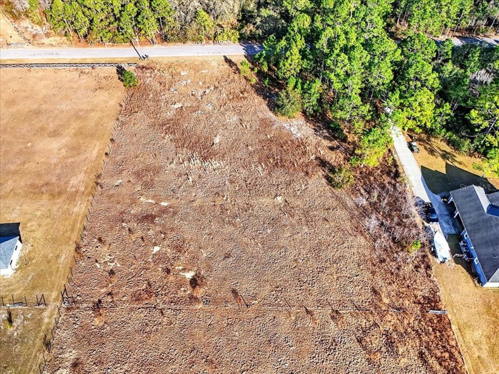 An aerial view shows a cleared, rectangular vacant lot bordered by trees and a road — SWEET HILL ROAD, POLK CITY, FL