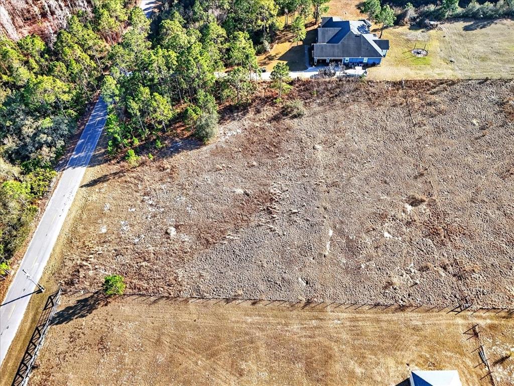 An aerial view shows a large, dry, fenced field next to a road and house — SWEET HILL ROAD, POLK CITY, FL