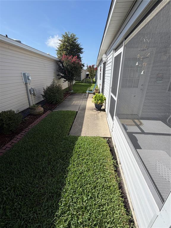 A narrow concrete walkway runs between a house with a screened porch and a neighboring wall — 2318 OAK BEND PLACE, THE VILLAGES, FL