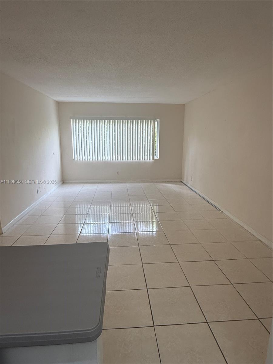 This room features light-colored tile flooring, plain walls, and a window with vertical blinds — 201 SE 6th Ave # 7, Pompano Beach FL 33060, POMPANO BEACH, FL