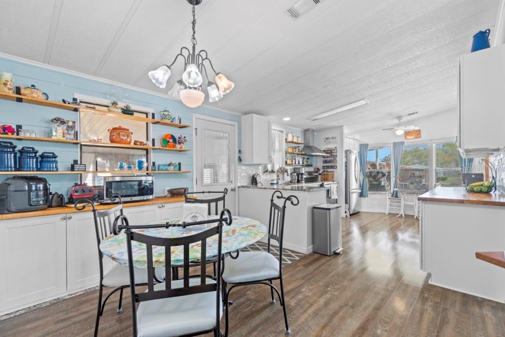 A kitchen and dining area with light blue walls, open shelving, and wood-look flooring — 35057 MCCULLOUGHS LEAP, ZEPHYRHILLS, FL