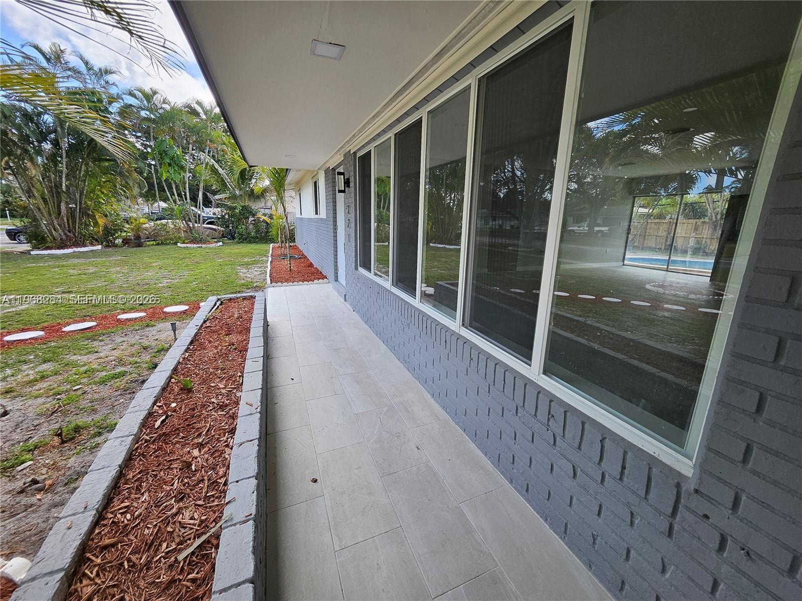 A gray brick house exterior features a tiled walkway, large windows, and a raised planter — 221 SW 53rd Ave, Plantation FL 33317, PLANTATION, FL
