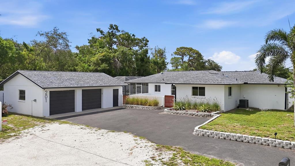 A white house with a detached two-car garage and a paved driveway under a blue sky — 201 HONORE AVENUE, SARASOTA, FL
