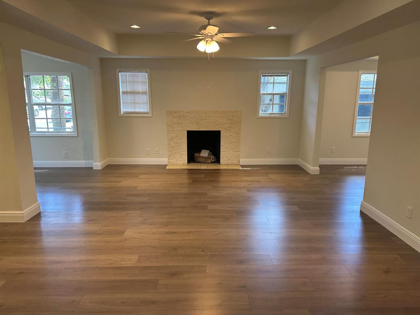 A living room features wood-look flooring, a stone fireplace, and a ceiling fan — 340 Walton Boulevard, West Palm Beach FL 33405, WEST PALM BEACH, FL