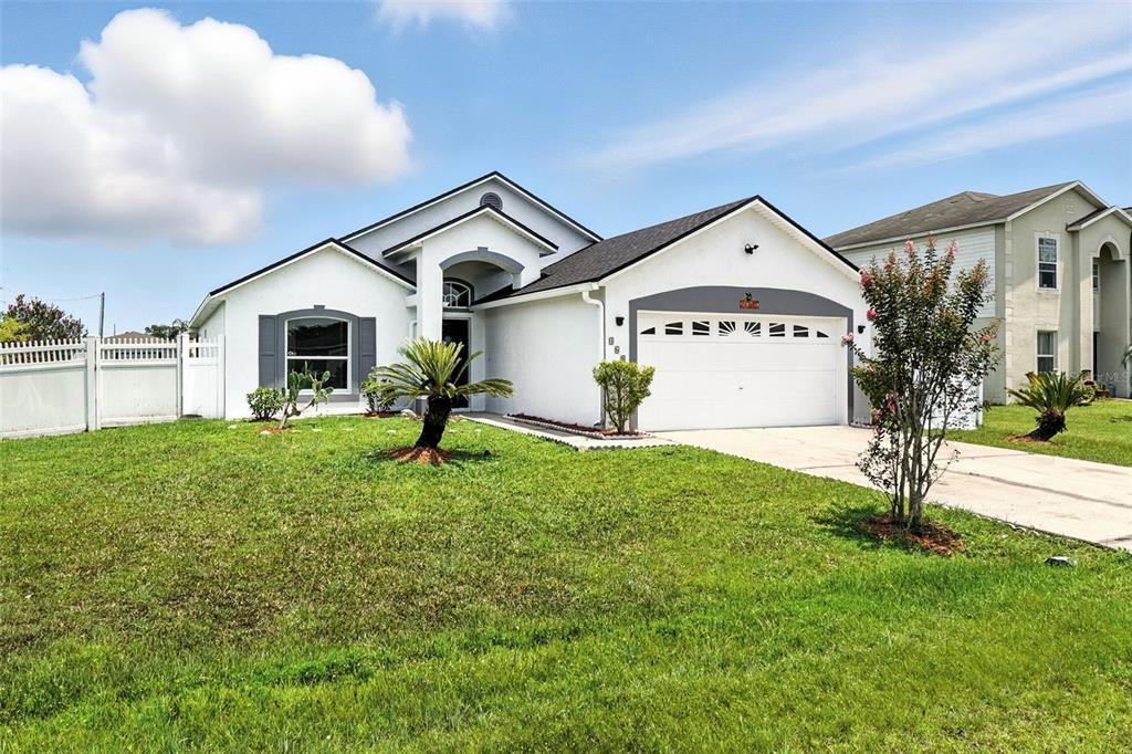 A single-story house with a white exterior, a two-car garage, and a front lawn — 460 MARTIGUES DRIVE, KISSIMMEE, FL