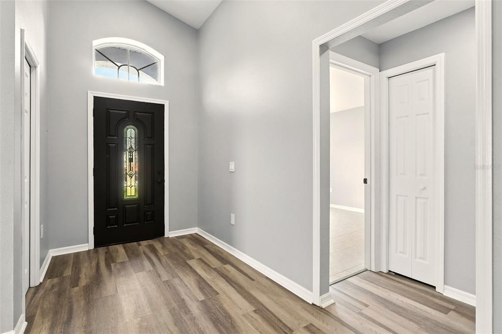 An entryway features a black front door, light gray walls, and wood-look flooring — 460 MARTIGUES DRIVE, KISSIMMEE, FL