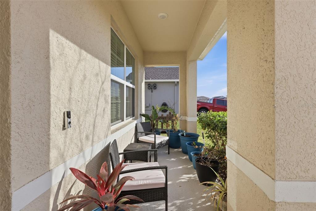 A covered outdoor patio features wicker chairs, potted plants, and a view of a neighboring house — 2029 APALACHICOLA LANE, SANFORD, FL