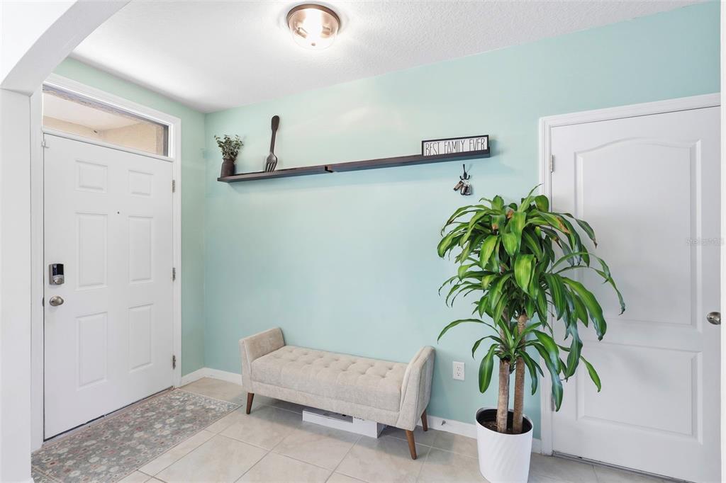 An entryway features light blue walls, a beige bench, a potted plant, and a wall shelf — 2029 APALACHICOLA LANE, SANFORD, FL