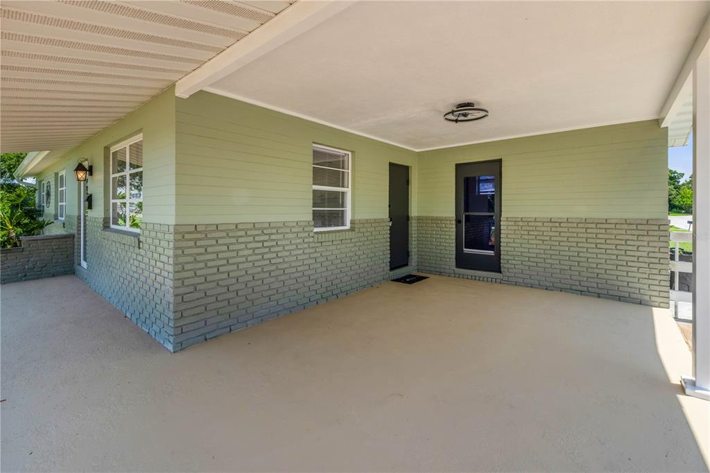 A covered porch with light green siding, a brick base, and two dark doors — 1807 S SEGRAVE STREET, SOUTH DAYTONA, FL