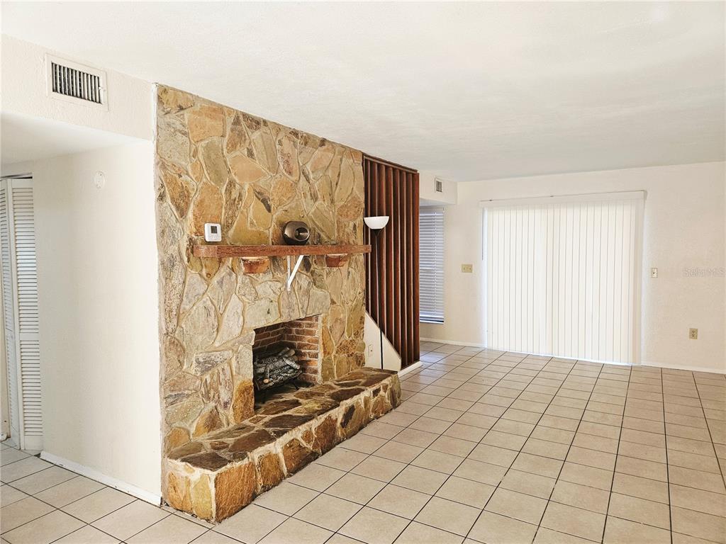 A living room features a large stone fireplace, tiled floors, and vertical wood slat room dividers — 1836 N CRYSTAL LAKE DRIVE UNIT 90, LAKELAND, FL
