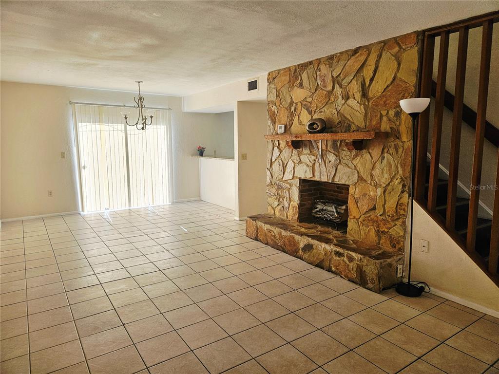 A living room features light tile flooring, a stone fireplace, and a sliding glass door — 1836 N CRYSTAL LAKE DRIVE UNIT 90, LAKELAND, FL