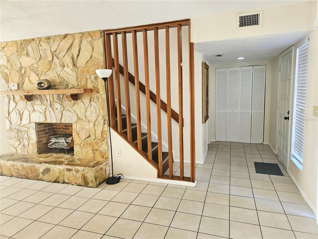 A living room features a stone fireplace, a wooden slat staircase railing, and tiled flooring — 1836 N CRYSTAL LAKE DRIVE UNIT 90, LAKELAND, FL