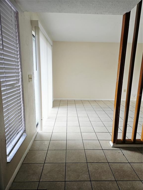 An empty room features beige tile flooring, light-colored walls, vertical blinds, and wooden room dividers — 1836 N CRYSTAL LAKE DRIVE UNIT 90, LAKELAND, FL