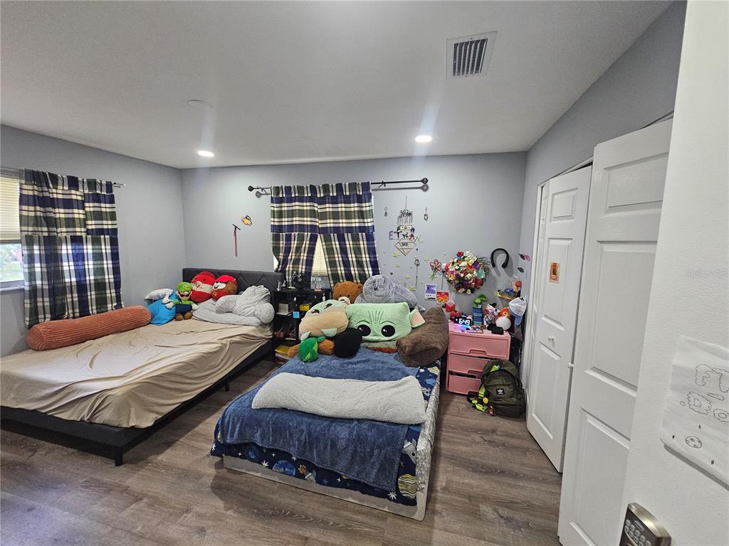 A bedroom with two beds, gray walls, wood-look flooring, and plaid curtains — 3110 22ND AVENUE W, BRADENTON, FL