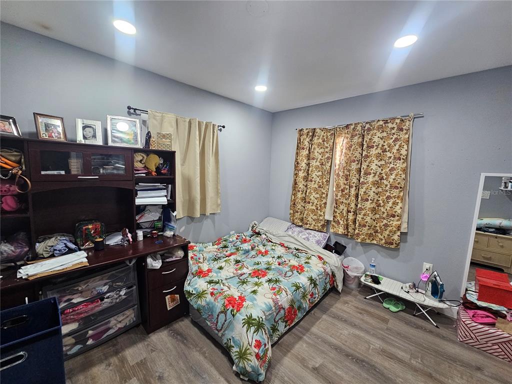 A bedroom features a bed with a floral comforter, a desk unit, and wood-look flooring — 3110 22ND AVENUE W, BRADENTON, FL