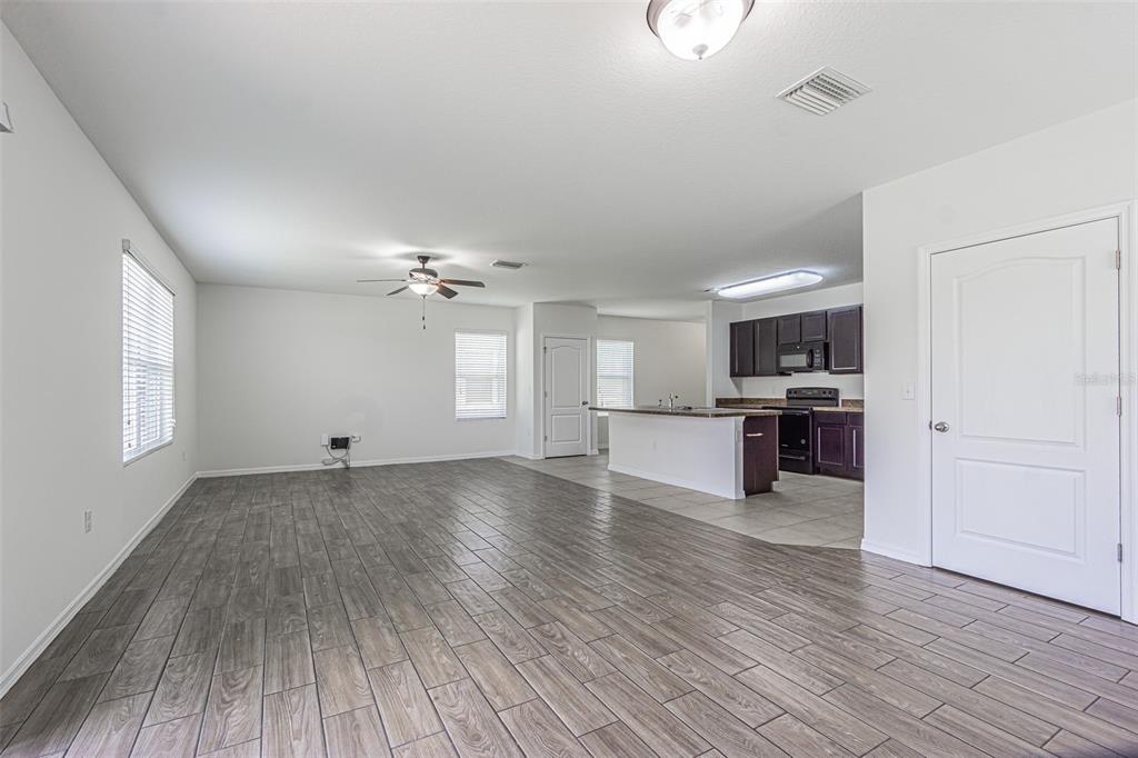 An open-concept living area features wood-look tile flooring, a ceiling fan, and a kitchen island — 10536 WHISPERING HAMMOCK DRIVE, RIVERVIEW, FL