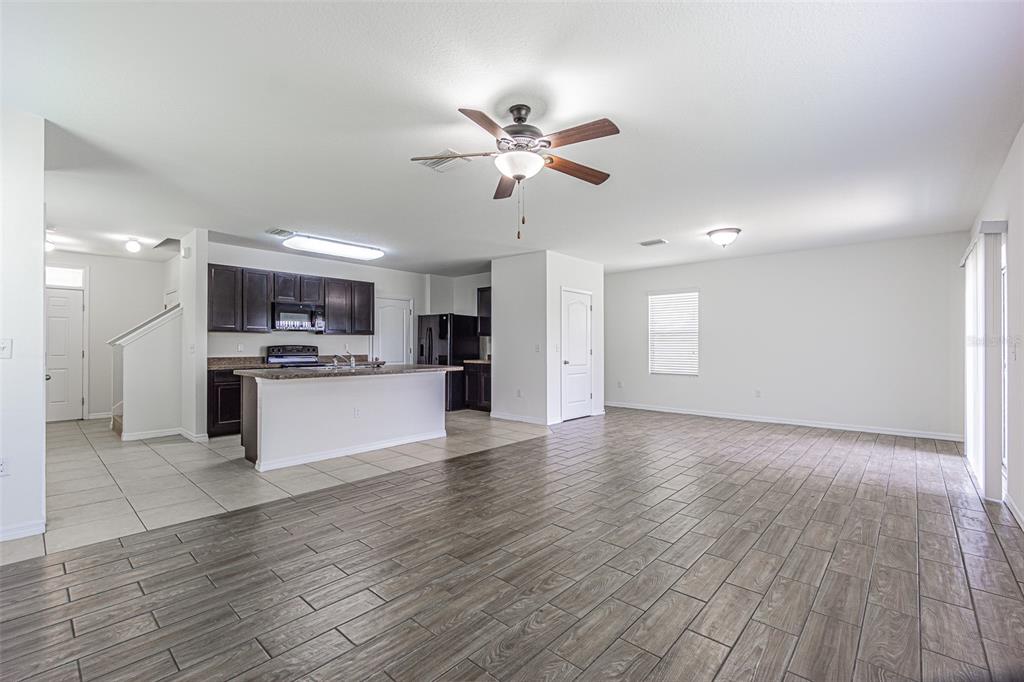 An open-concept kitchen with dark cabinets and an island overlooks a spacious tiled living area — 10536 WHISPERING HAMMOCK DRIVE, RIVERVIEW, FL