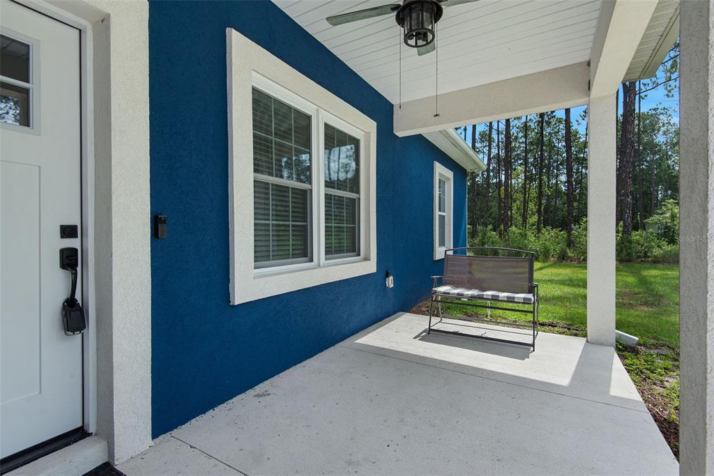 A blue stucco house exterior features a covered front porch with a metal bench — 4220 PALATKA BOULEVARD, HASTINGS, FL