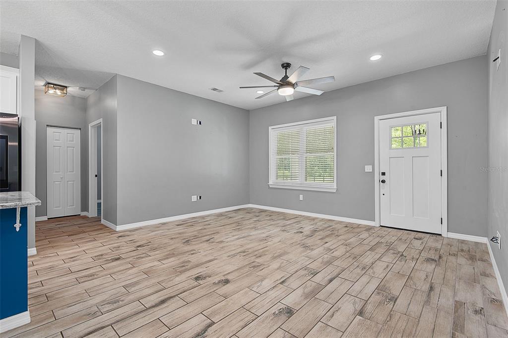 A living room with gray walls, wood-look tile flooring, a ceiling fan, and white trim — 4220 PALATKA BOULEVARD, HASTINGS, FL