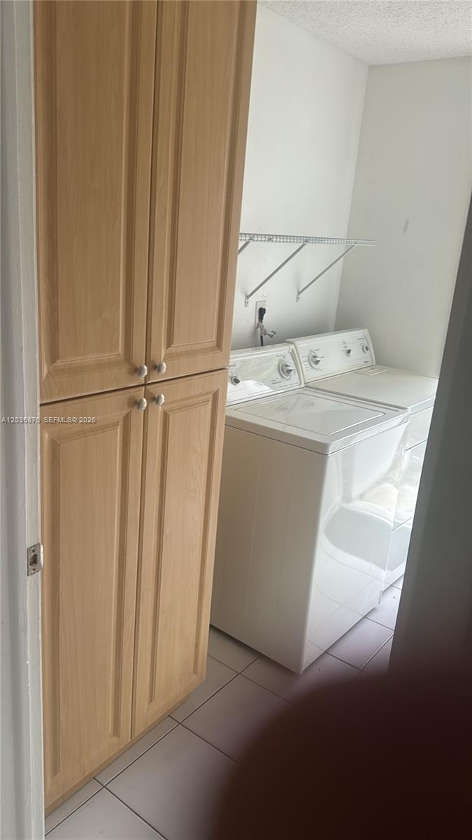 A laundry room features a tall wooden cabinet next to a white washer and dryer — 830 W 75th St # 1, Hialeah FL 33014, HIALEAH, FL