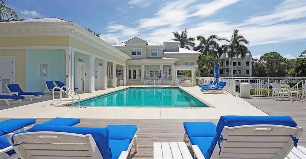 A swimming pool sits in front of a multi-story building with lounge chairs on deck — 7840 34TH AVENUE W UNIT 102, BRADENTON, FL