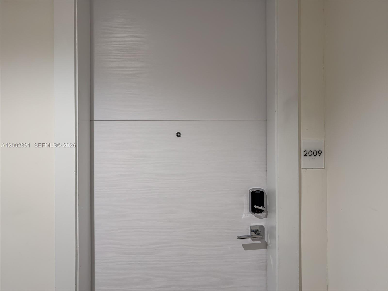 A white door with a digital lock and a unit number sign labeled 2009 — 2000 Metropica Way # 2009, Sunrise FL 33323, SUNRISE, FL