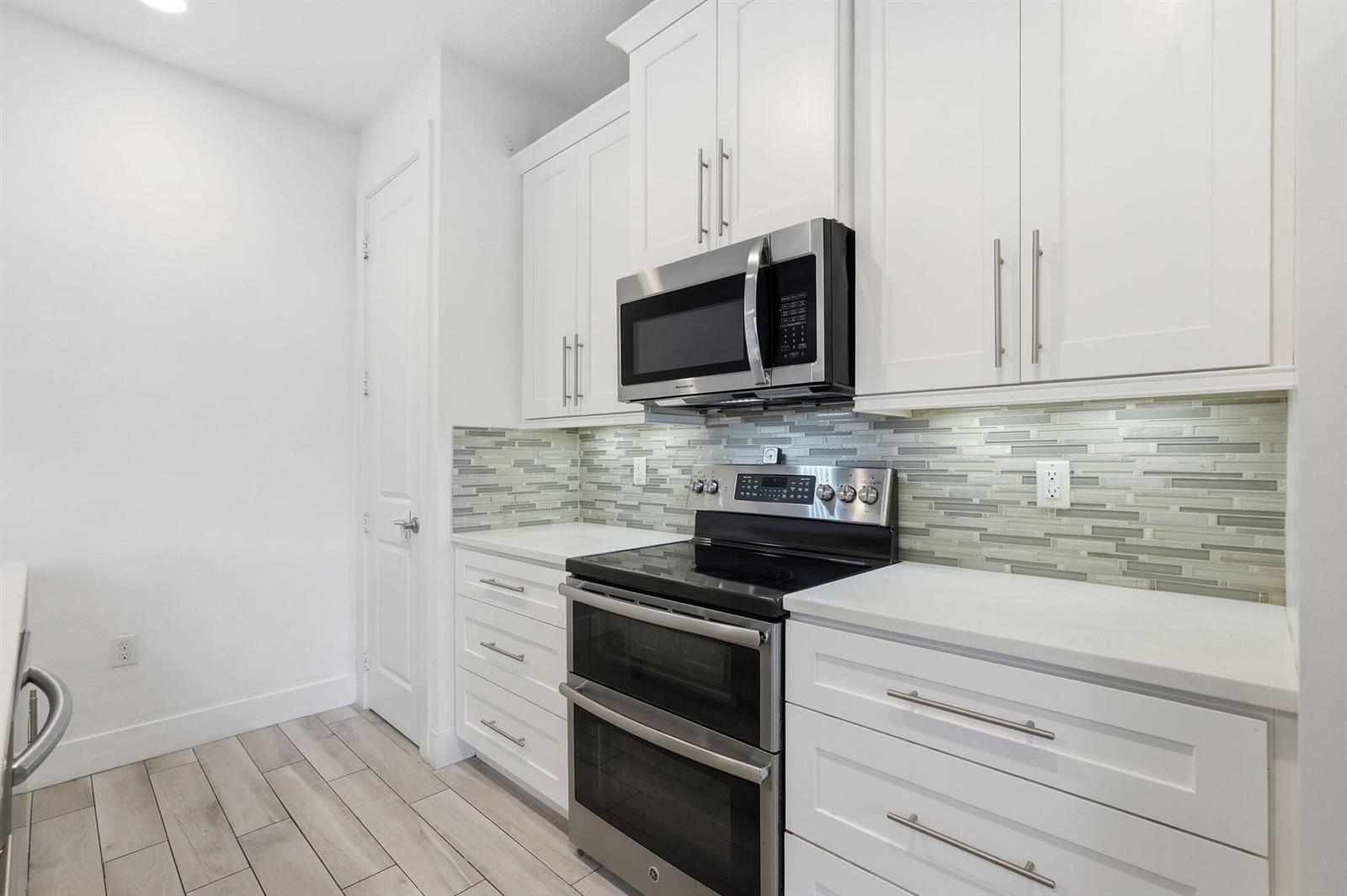 A kitchen features white cabinets, stainless steel appliances, and a glass tile backsplash — 3193 Santa Catalina Place, FL 33467, FL