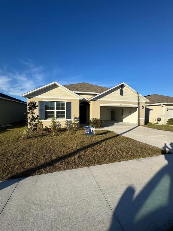 A single-story suburban house with a tan exterior, dark shutters, and an attached two-car garage — 528 BOARDWALK AVENUE, HAINES CITY, FL