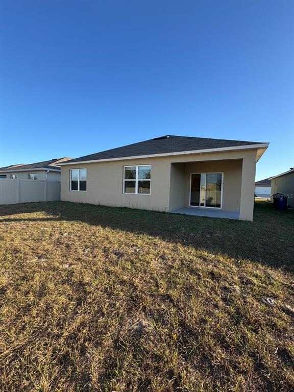 The rear exterior of a single-story house features a covered patio and a fenced yard — 528 BOARDWALK AVENUE, HAINES CITY, FL