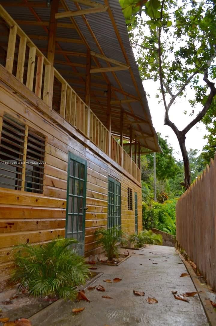 A wooden house with a balcony and a concrete walkway surrounded by lush greenery — 20 RM Cardiff Hall Villa St Ann, Jamaica, NA, NA