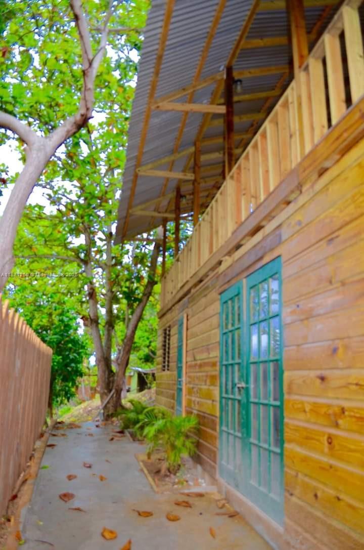 A wooden house exterior features a covered balcony, green-framed glass doors, and a concrete walkway — 20 RM Cardiff Hall Villa St Ann, Jamaica, NA, NA