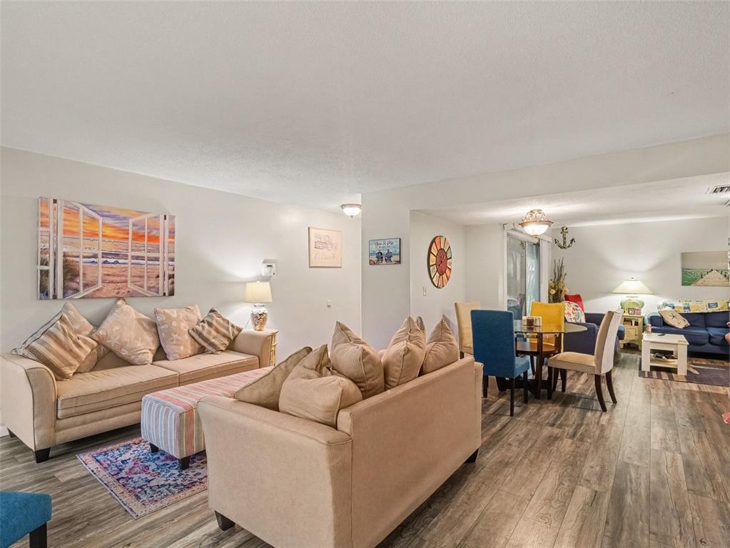 A living room and dining area with light-colored sofas, wood-look flooring, and coastal decor — 908 BYRON LANE UNIT 6, SARASOTA, FL