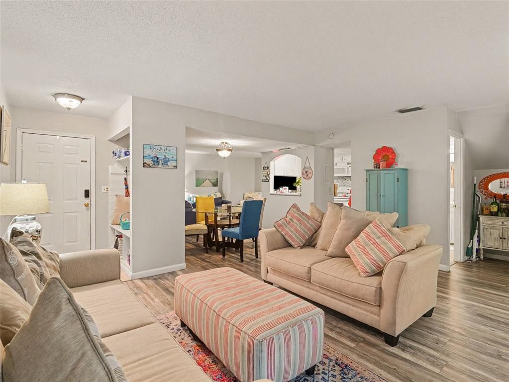 A living room with light-colored sofas, a striped ottoman, and an adjacent dining area — 908 BYRON LANE UNIT 6, SARASOTA, FL