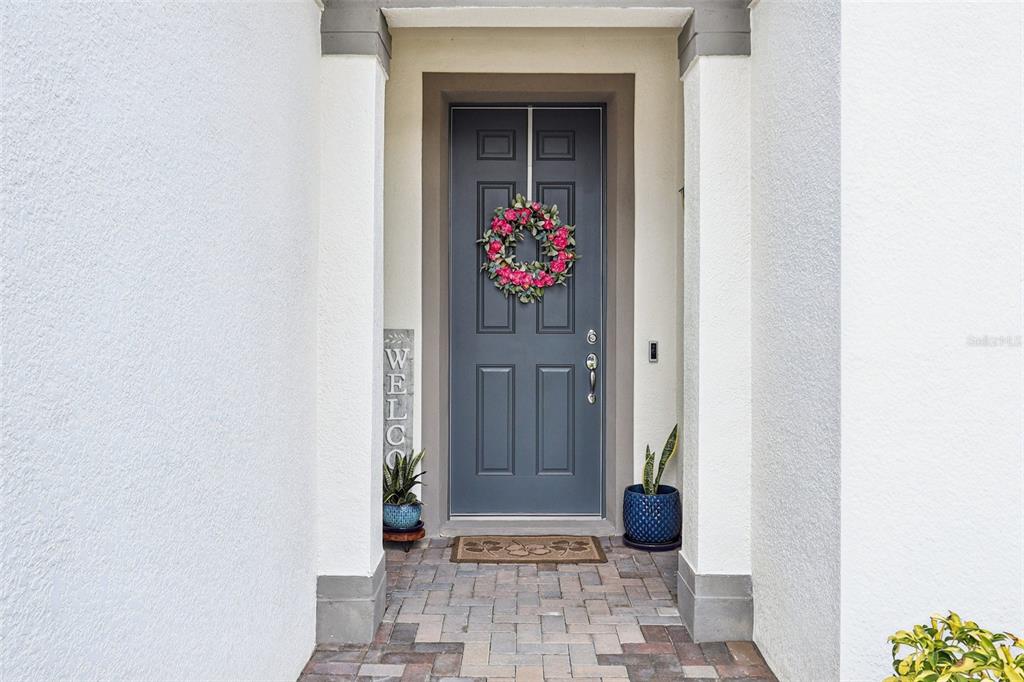 A dark gray front door with a floral wreath is framed by white stucco columns — 2015 SPRING SHOWER CIRCLE, KISSIMMEE, FL