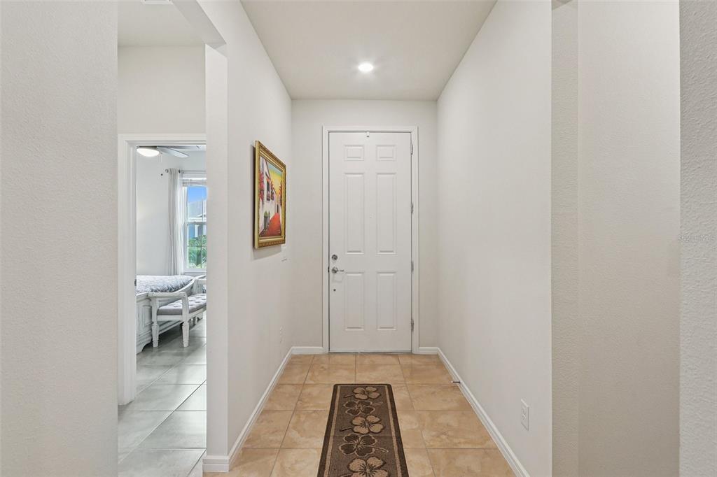 A tiled entryway leads to a white front door with a framed picture on the wall — 2015 SPRING SHOWER CIRCLE, KISSIMMEE, FL
