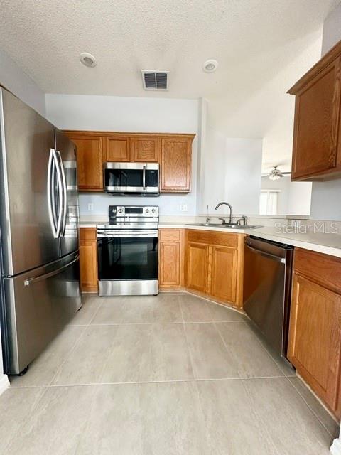 A kitchen features stainless steel appliances, light wood cabinets, and light-colored tile flooring — 4903 WATERSIDE POINTE CIRCLE, ORLANDO, FL