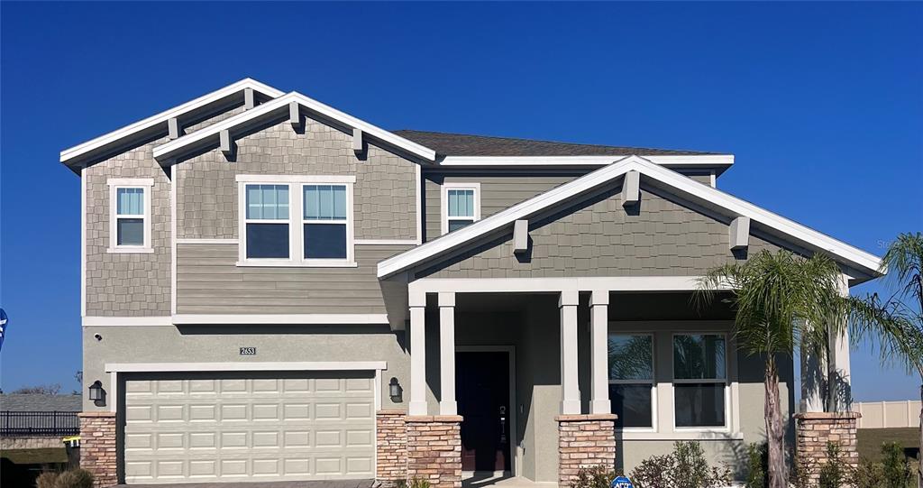 A two-story house with a stone-accented porch, gray siding, and a two-car garage — 2653 RUNNERS CIRCLE, CLERMONT, FL