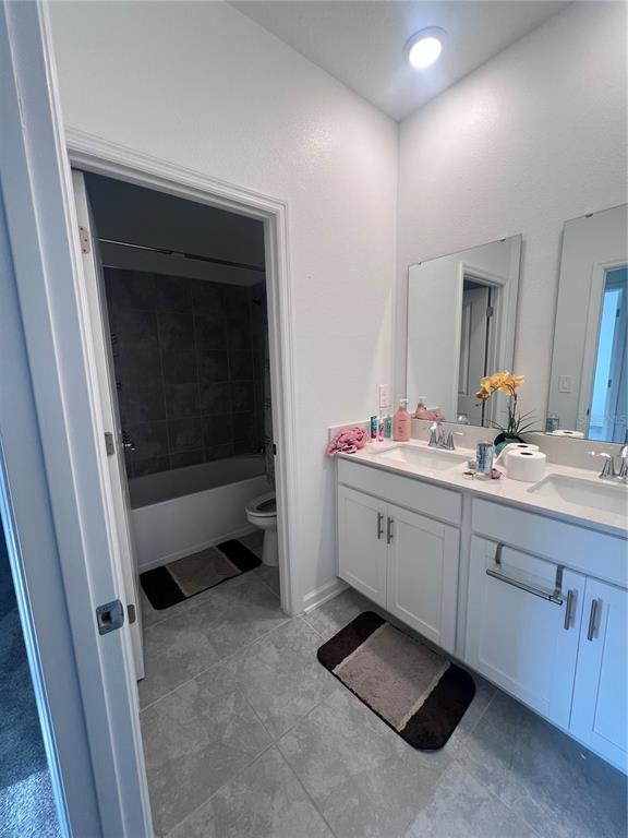 A bathroom features a double vanity with white cabinets, gray tile floors, and a tub-shower — 2653 RUNNERS CIRCLE, CLERMONT, FL