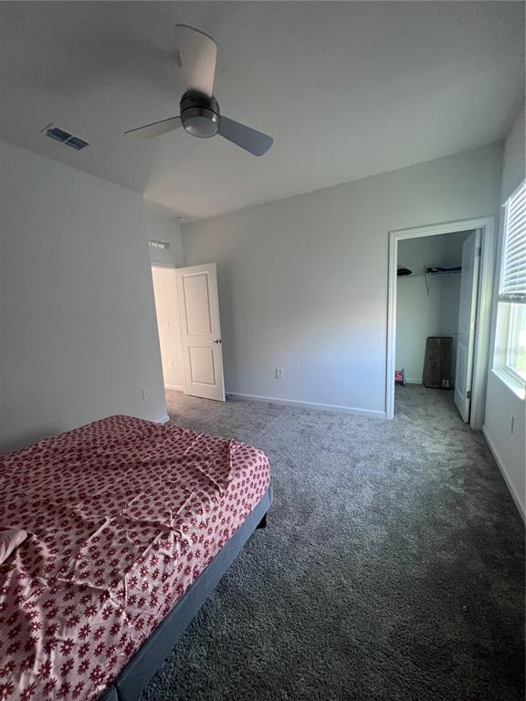 A bedroom features gray carpeting, a ceiling fan, and an open doorway to a closet — 2653 RUNNERS CIRCLE, CLERMONT, FL