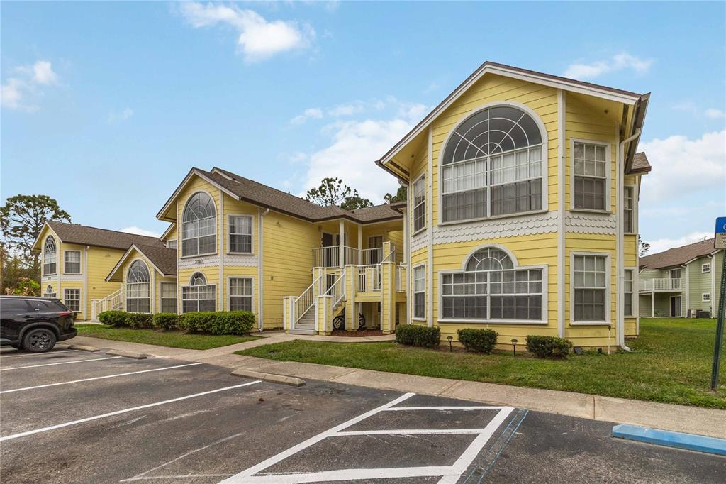 A yellow multi-story apartment building with arched windows and a parking lot in front — 2040 ROYAL BAY BOULEVARD UNIT 30, KISSIMMEE, FL