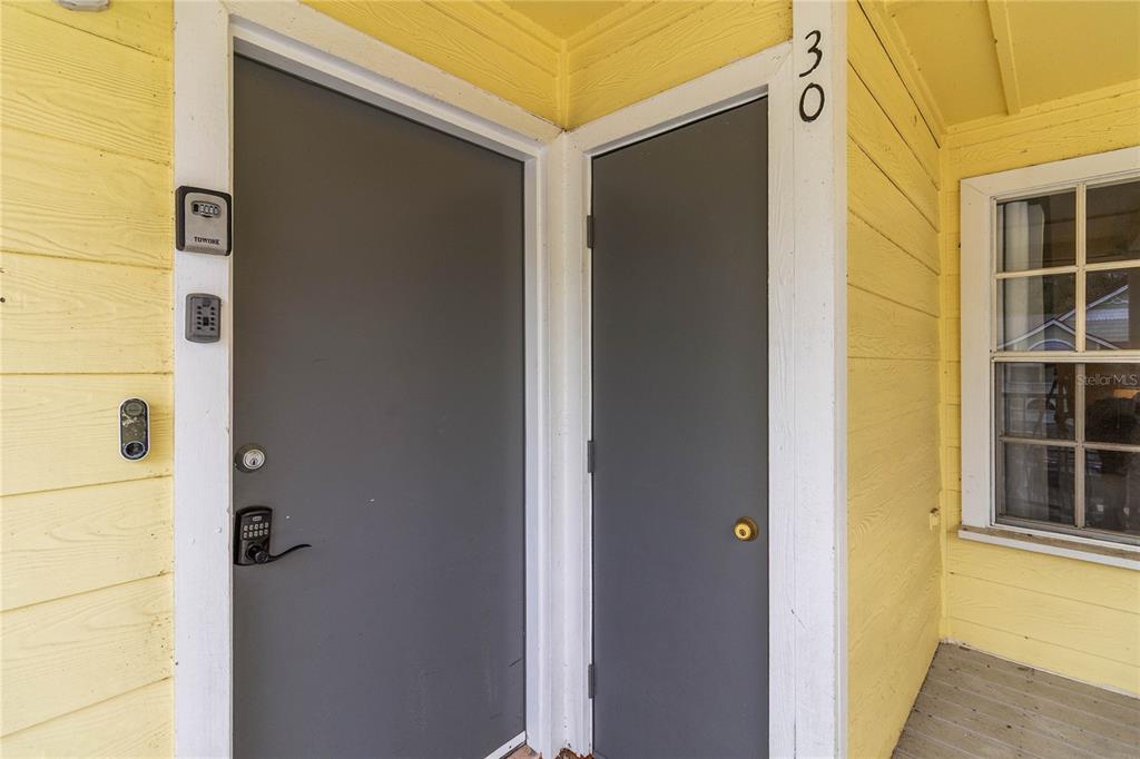 A yellow exterior wall features two gray doors, a window, and multiple electronic locks — 2040 ROYAL BAY BOULEVARD UNIT 30, KISSIMMEE, FL