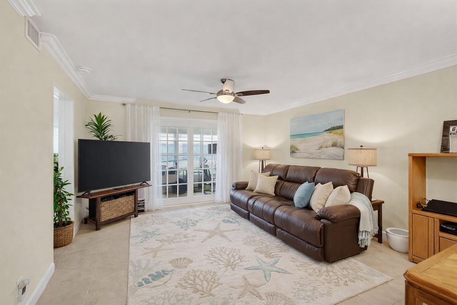 A living room features a brown leather sofa, a coastal-themed rug, and glass patio doors — 19000 Stewart Circle # 4, Boca Raton FL 33496, BOCA RATON, FL