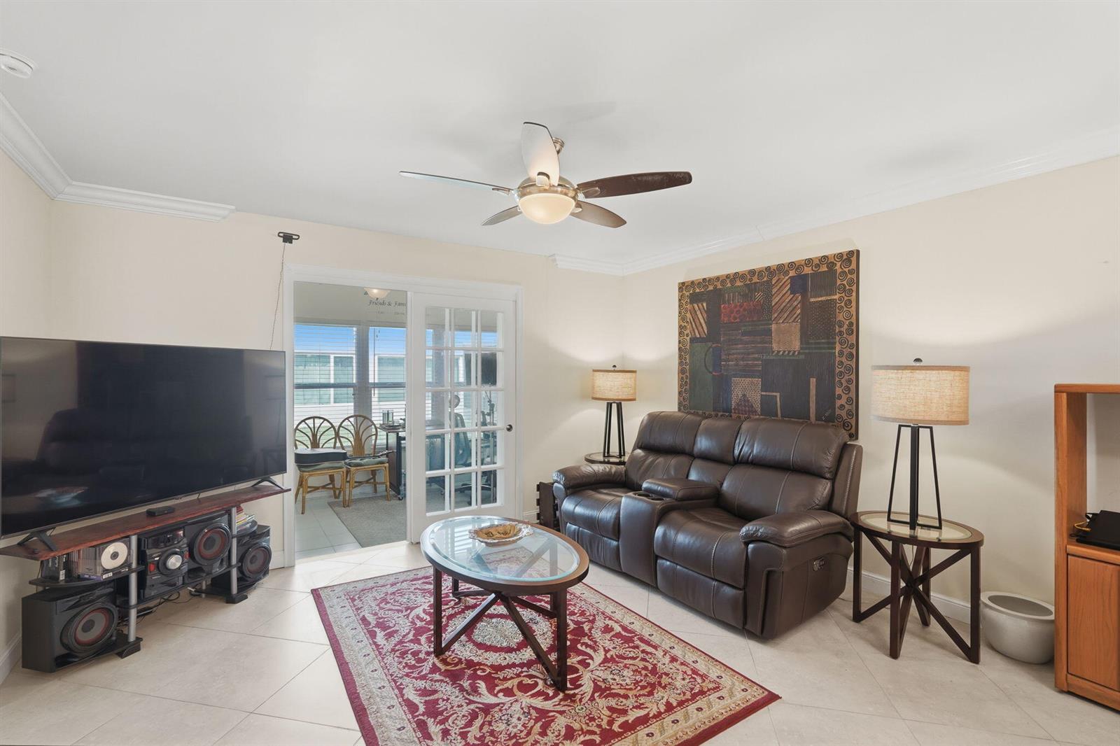 A living room features a brown leather sofa, glass coffee table, and a large television — 19000 Stewart Circle # 4, Boca Raton FL 33496, BOCA RATON, FL