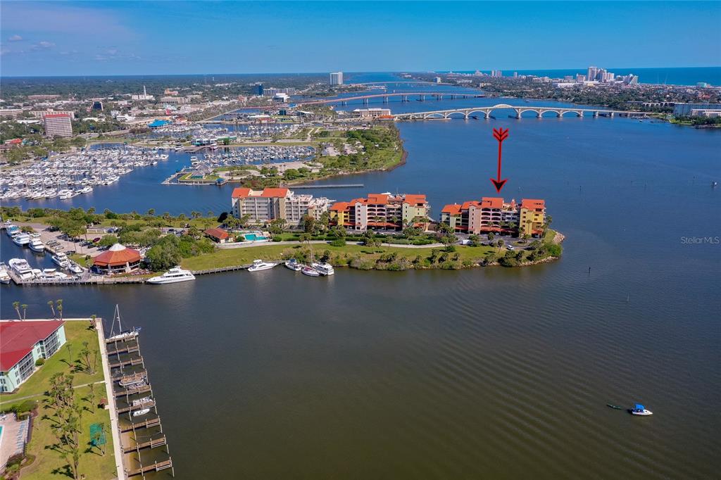 An aerial view shows a multi-story waterfront condominium complex on a peninsula near a bridge — 731 MARINA POINT DRIVE UNIT 731, DAYTONA BEACH, FL