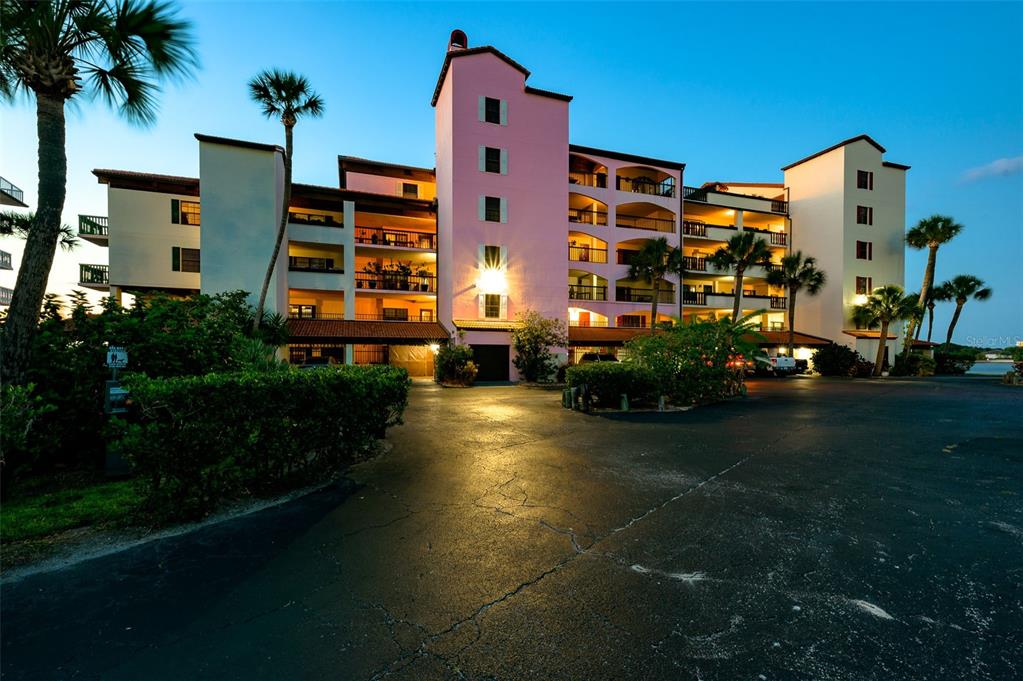 A multi-story pink and white apartment building stands above a paved parking lot at dusk — 731 MARINA POINT DRIVE UNIT 731, DAYTONA BEACH, FL