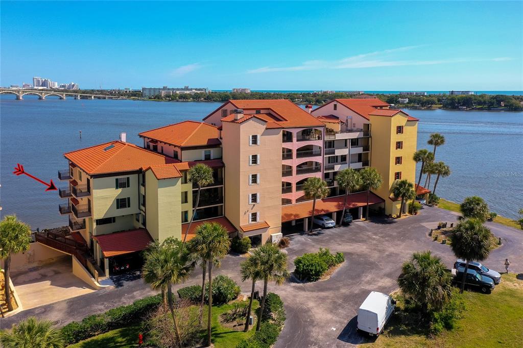 An aerial view shows a multi-story waterfront apartment building with balconies and a parking lot — 731 MARINA POINT DRIVE UNIT 731, DAYTONA BEACH, FL